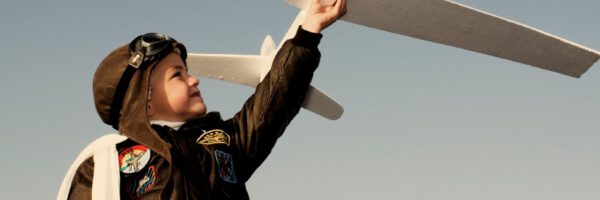 Ein Kind in einer Fliegerjacke und mit Pilotenkappe hĂ€lt ein groĂes weiĂes Modellflugzeug hoch in den Himmel. Im Hintergrund ist ein klarer blauer Himmel zu sehen. Unten rechts steht das Wort âZukunftsmutâ. Ein Kind in einer Fliegerjacke und mit Pilotenkappe hĂ€lt ein groĂes weiĂes Modellflugzeug hoch in den Himmel. Im Hintergrund ist ein klarer blauer Himmel zu sehen. Unten rechts steht das Wort âZukunftsmutâ.